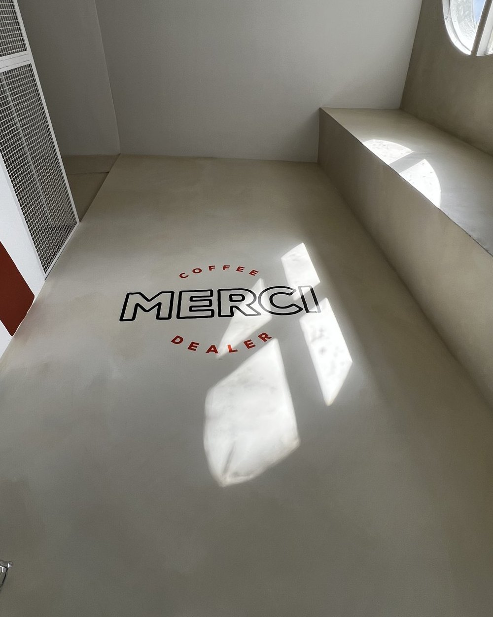 Logo de Merci Coffee Dealer aplicado en la pared del local